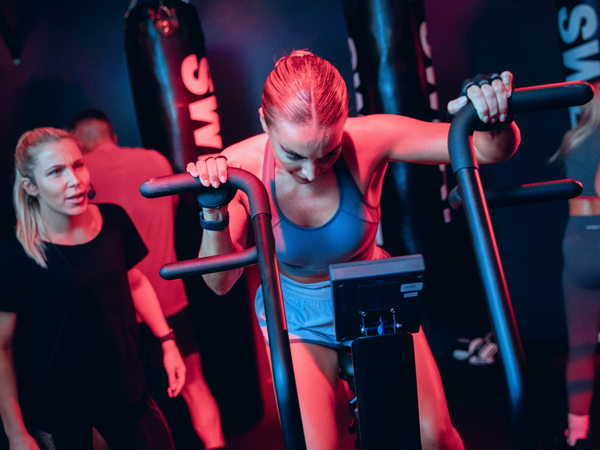 Instructor guiding woman on excercise bike in SWEAT class at 3-1-5 Health Club Lancaster, UK.